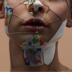 a woman's face is covered in gold wire and has flowers on her neck