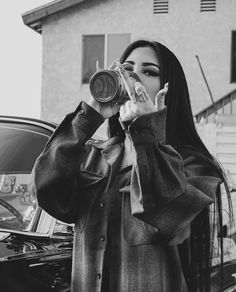 a woman with long hair is taking a selfie in front of a parked car