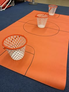 three basketball hoops sitting on top of an orange mat in the middle of a gym