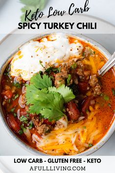 a white bowl filled with chili and sour cream topped with sour cream, cilantro