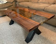 a wooden table sitting on top of a carpeted floor next to a couch in a living room