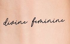 the word divine feminine written in cursive ink on a woman's back