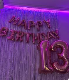 the number thirteen balloon is displayed in front of a purple wall with streamers that say happy birthday