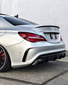 the rear end of a silver mercedes cla parked in front of a white building