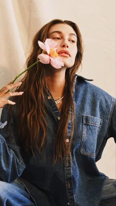 a woman with long hair holding a flower in her mouth