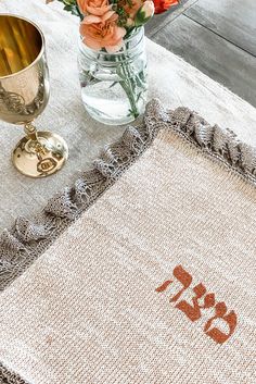 a table with flowers and a vase on top of it next to a cross stitch rug