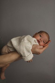 a baby is being held in the air by someone's hand while holding it