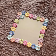 there is a mirror with crocheted flowers in the shape of a heart on it