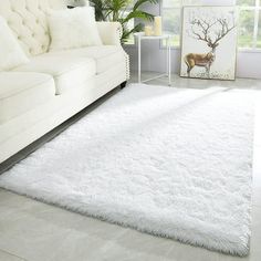 a living room with a white couch and rugs on the floor in front of a window