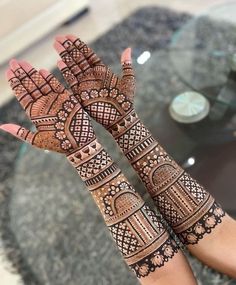 two hands with henna tattoos on them, one is showing off the intricate design