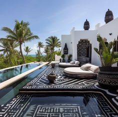 an outdoor area with black and white tiles on the floor, potted plants, and pool