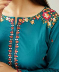 a woman wearing a green blouse with flowers on it