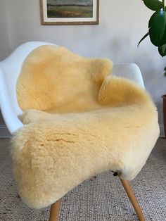 a white chair with a yellow sheepskin seat cover on it's back and legs