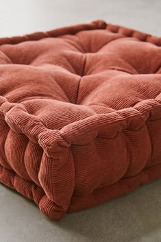 an orange square cushion on the floor