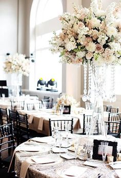 a tall vase filled with lots of flowers on top of a table covered in place settings