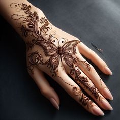 a woman's hand with henna tattoos on it and an intricate butterfly design