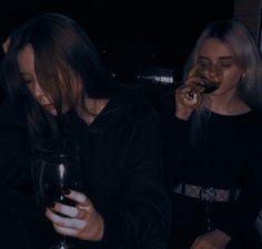 two women sitting next to each other drinking wine