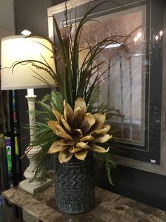 a vase filled with lots of flowers on top of a table next to a lamp