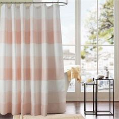 a white and pink shower curtain next to a bath tub with a window in the background