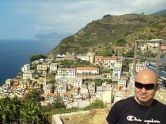 a man standing on top of a hill next to the ocean with buildings in the background