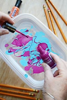 a person is painting on a plastic container