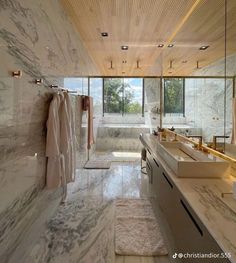 a large bathroom with two sinks and marble counter tops in front of glass doors that open to the outdoors