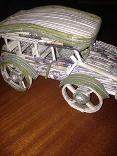 a toy car made out of newspapers on a wooden table with wheels and rims