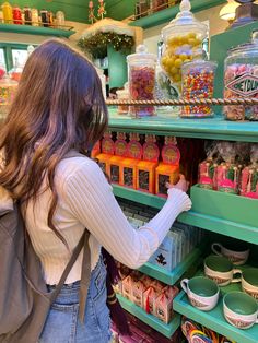 a woman is looking at candy in a store shelf with shelves full of candies and lollipops