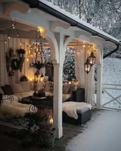 a covered porch with lights on the ceiling and couches in the snow under it