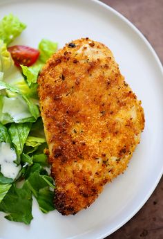 a white plate topped with chicken, salad and lettuce on top of it