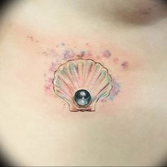 a woman's stomach with a small tattoo on the side of her belly and an ocean shell