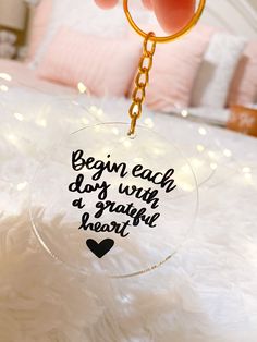 a hand holding a glass keychain that says begin each day with a grateful heart