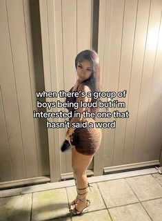 a woman standing in front of a door with her legs crossed and the words, when there's a group of boys being loud but i'm interested in the one that hasn't said a word