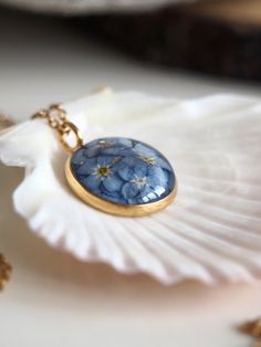 a close up of a necklace on a shell with flowers in the center and gold chain