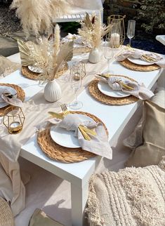 the table is set with white and gold plates, napkins, and silverware