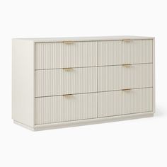 a white dresser with four drawers and two gold pulls on the bottom, against a white background