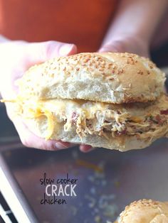 a hand holding a sandwich with meat and cheese on it in front of a plate