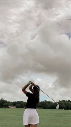 a woman standing on top of a lush green field holding a golf racquet