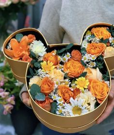 a person holding a mickey mouse shaped box filled with flowers