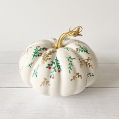 a white pumpkin decorated with gold leaves and berries