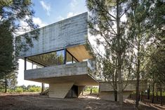 the house is surrounded by pine trees and has a concrete structure that sits on top of it