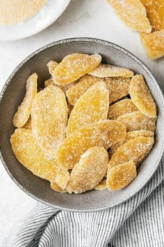 a bowl filled with sugared sugar on top of a white tablecloth next to two plates