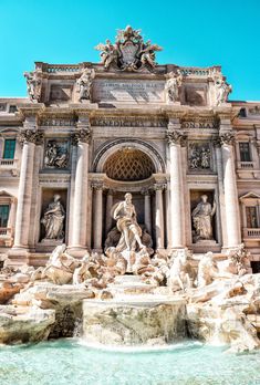 an ornate building with statues and fountains in front