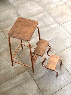 two wooden stools sitting on top of a tile floor next to a table and chair