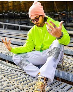 a man sitting on top of a metal grate wearing an orange hat and green jacket