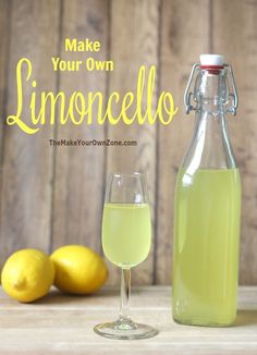 a bottle of lemonade next to a wine glass and two lemons on a table