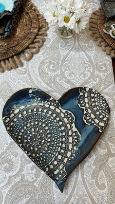 a heart shaped dish sitting on top of a table next to two vases with flowers in them