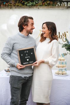 a man and woman standing next to each other holding a sign