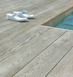 a pair of white slippers sitting on top of a wooden floor next to a pool