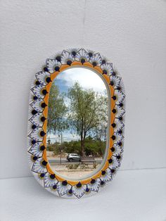 a mirror hanging on the wall with a reflection of a tree in it's center